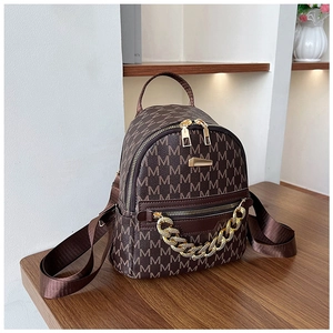 Close-up of brown faux leather backpack with M-pattern print and chunky gold chain