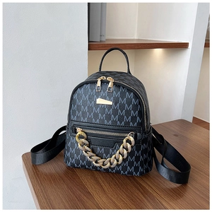 Detail of mini black backpack with gold chain and M-letter monogram pattern texture