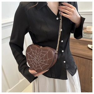 Detailed view of dark brown heart-shaped crossbody bag with white spiderweb embroidery