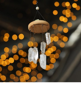 Detail of natural white crystal wind chime with wood base and gold bokeh background