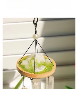 Close-up of white crystal point on bamboo base with green moss for hanging wind chime
