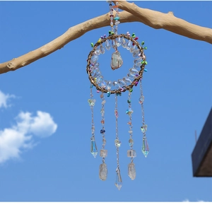 Close-up of tree of life dreamcatcher with crystals hanging from a tree branch