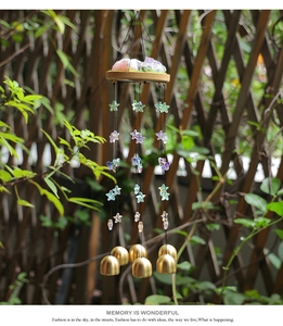 Détail d'un carillon avec pierres de cristal roses, perles étoilées et cloches dorées
