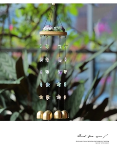 Détail d'un carillon en améthyste avec étoiles et cloches en laiton dans un jardin