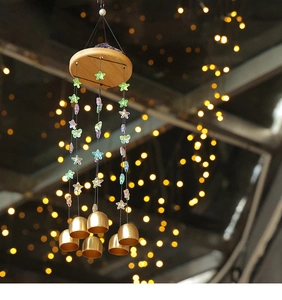 Détail d'un carillon éolien avec cloches en laiton et décorations d'étoiles colorées