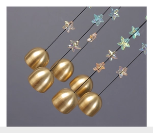 Gros plan de cloches en métal doré mat et perles d'étoiles irisées sur un carillon