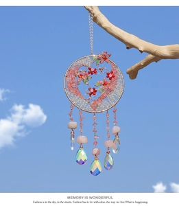 Detail of tree of life suncatcher with pink crystals and beads hanging from a tree branch