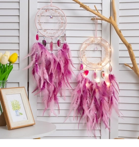 Detail eines rosa Traumfängers mit Federn und warmen LED-Lichtern in einer Wohnung