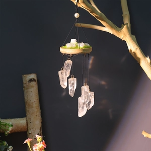 Hanging wind chime with natural white crystal pillars and a moss wooden base