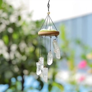 Natural white crystal wind chime with wood base and moss decor against garden background