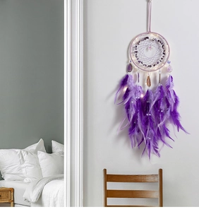Detail eines lila Traumfängers mit Federn, Naturkristallen und LED-Beleuchtung an der Wand