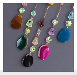 Detailed close-up of colorful Halloween agate stone pendants with ghost beads and gold chains