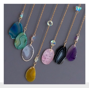 Detailed view of colorful natural agate crystal slices with elegant golden butterfly chains