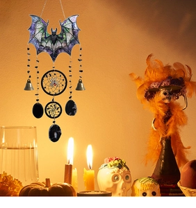 Detail of Halloween bat pendant with bells and stones against a festive candlelit backdrop