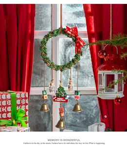 Close-up of Christmas wreath with metal bells and Merry Christmas sign on red background
