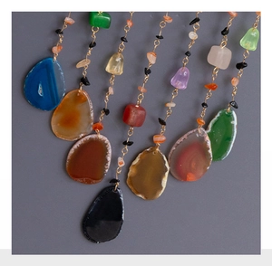 Detail of natural agate stone necklaces with gold chains and colorful gemstone pendants