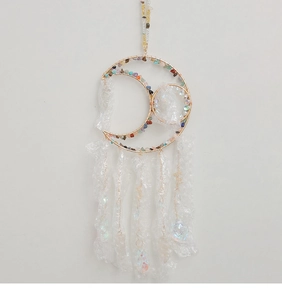 Detail of moon-shaped suncatcher with colorful crushed crystals and clear drop pendants