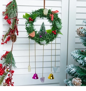 Christmas wreath with crystals, pine needles, red berries and festive bells on wood background