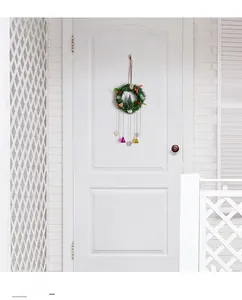Detail of Christmas wreath door hanger with bells, mini tree, and red berries