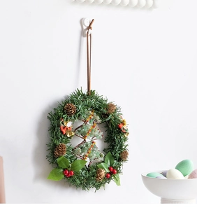 Detail of a handmade Christmas wreath with pine needles, red berries, and stone tree charm