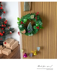 Detail of Christmas wreath with bells, pine needles and crystals hanging on a wooden door