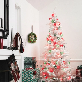 Detail of red and green ball string lights wrapped on a white Christmas tree