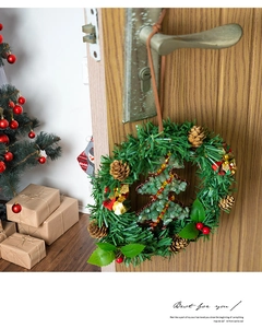 Detail of Christmas wreath ornament with pine needles, cones and berries on a door