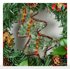 Close-up of handmade wire Christmas tree ornament with green stones and red beads