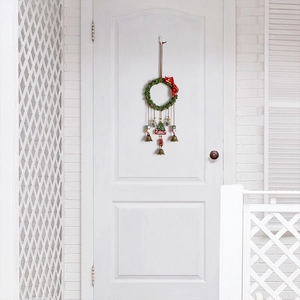 Christmas wreath door hanger with green vines, red bows, metal bells, and Merry Christmas sign