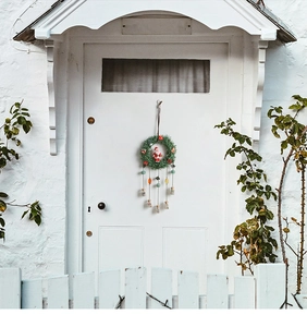 Detail of Christmas wreath with Santa doll and glass bottles hanging on a white door