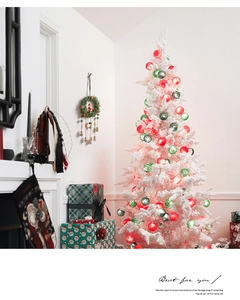 Flocked white Christmas tree with festive red and green ornaments in a cozy room