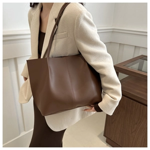 Dettaglio della borsa tote in pelle marrone scuro con cuciture verticali minimaliste