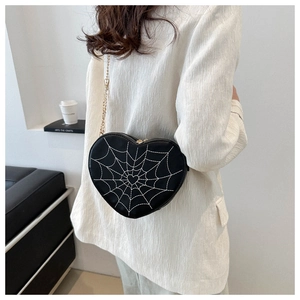Close-up of heart-shaped crossbody bag with spider web embroidery and gold chain strap