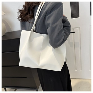 Dettaglio della borsa tote in morbida pelle bianca con cuciture verticali e tracolla lunga