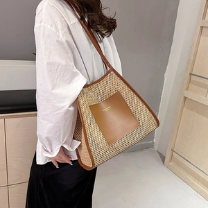 Borsa tote in paglia minimalista con finiture in pelle marrone indossata a spalla, stile