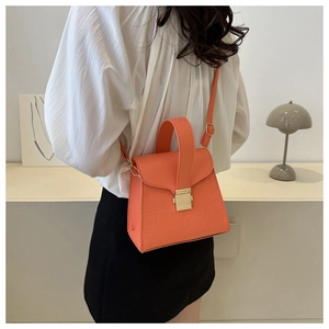 Chic orange faux crocodile leather handbag shown worn by a model in a modern interior