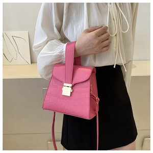 Detailed side view of bright pink croc-embossed mini handbag with golden metal buckle