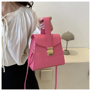 Detail showing bright pink crocodile pattern texture and golden square metal lock on handbag