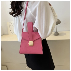 Side view of pink crocodile-embossed leather handbag with adjustable shoulder strap