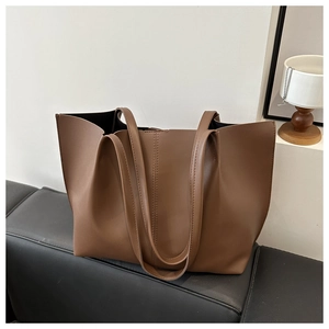 Dettaglio della borsa tote vintage in pelle marrone con grana naturale su un divano