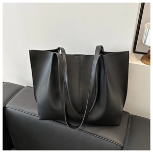Dettaglio borsa tote nera opaca con cuciture doppie eleganti su un divano in pelle nera