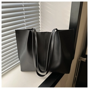 Dettaglio di una borsa tote nera in pelle con eleganti doppie cuciture verticali esterne