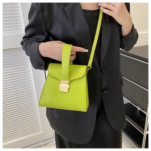 Close-up of vibrant lime green crocodile pattern leather bag with sleek metal lock detail