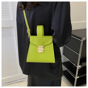 Detail of neon green crocodile texture handbag with gold buckle and slim strap