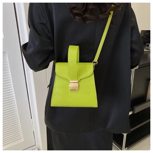 Detail of neon green faux leather handbag with crocodile texture and gold buckle