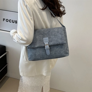 Fashionable grey felt crossbody bag with blue straps shown on a model in a modern interior