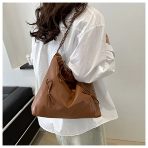 Detailed view of brown soft leather tote with bow drawstring and metal chain strap