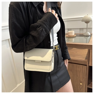 Detalle de bolso cuadrado de cuero blanco roto con correa ancha gris oscuro