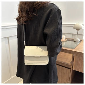Bolso bandolera beige minimalista lucido por una modelo en un ambiente de oficina real
