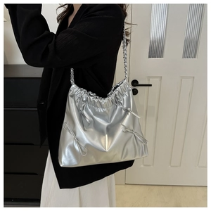 Detail of silver metallic bucket bag with ribbon decoration and delicate chain strap